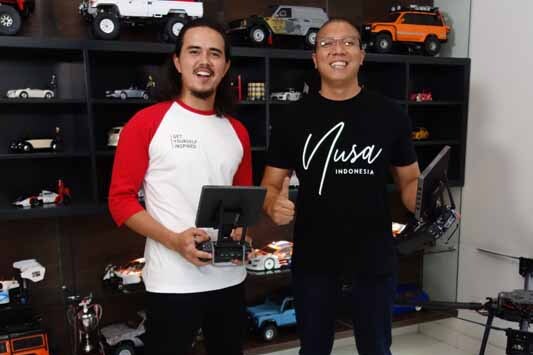 Rama Tribudiman & David John Schaap berfoto di depan koleksi remote control